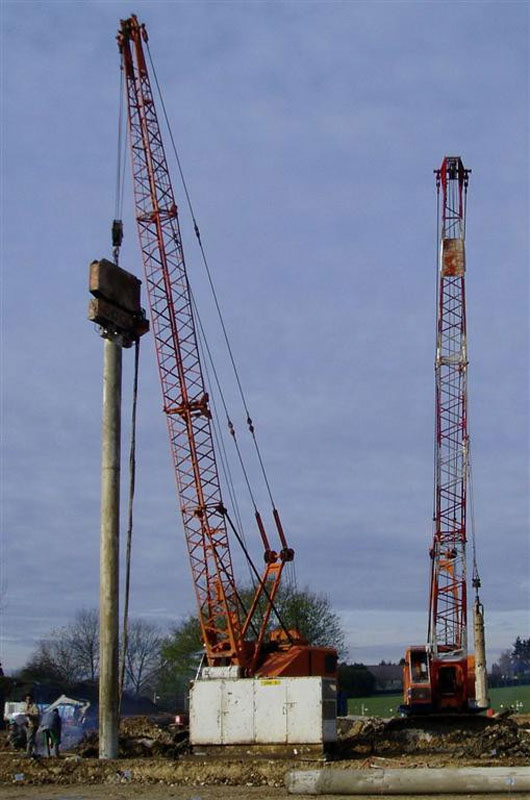 Atelier de forage avec une pelle pour vibrofoncer le tube et l'autre pour forer et curer le pieu.